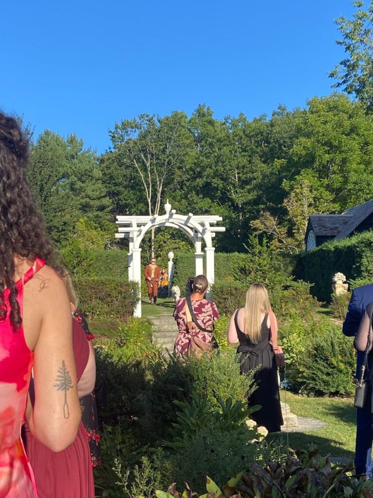 A dog walking down the aisle at an outdoor garden wedding
